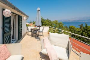 a balcony with chairs and an umbrella and a table at Holiday Home Dora in Splitska +61 photos
