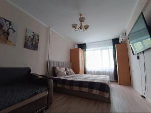 a bedroom with a bed and a couch and a window at Уютная 1 комн квартира посуточно в Балхаше Жидебай Батыра, 11 in Balqash