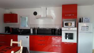 a red kitchen with white appliances and red cabinets at Gîte détente Domaine de Helles -Spa Privatif et Sauna in Poullaouen +38 photos