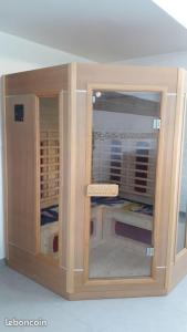 a wooden cabinet with a glass door in a room at Gîte détente Domaine de Helles -Spa Privatif et Sauna in Poullaouen