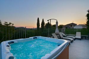 a hot tub sitting on a patio with two chairs at Villa Verde, Kobitsi Corfu in Corfu