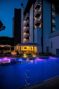 una piscina di fronte a un edificio di notte di Hotel Bella Venezia Mare a Lignano Sabbiadoro