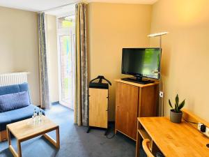 a living room with a tv and a blue couch at Hotel Rheinpark Rees in Rees