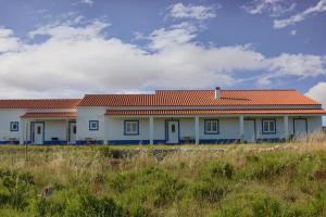 a white house with an orange roof on a field at Monte da Fome Aguda in Odeceixe