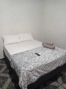 a bed in a room with a white wall at Kitnet Penha CEFAN ADVEC in Rio de Janeiro