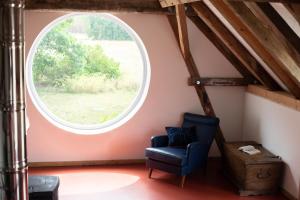 una finestra rotonda in una stanza con una sedia di loft-feeling im Cottage! a Brandenburg an der Havel
