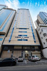 a tall building with cars parked in a parking lot at فندق الأحباب الكبرى الفندقية ٢ in Makkah