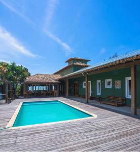 a house with a swimming pool and a wooden deck at Casa pe na areia em Buzios in Búzios