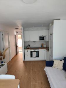 a kitchen and living room with white cabinets and a couch at Apartamento Ferrandis Benicasim in Benicàssim