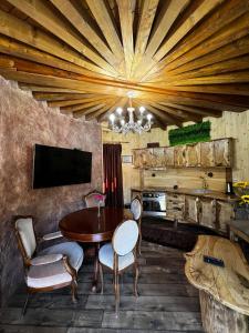 una sala da pranzo con tavolo, sedie e TV di Приказната къщичка на Смърфовете a Krayni Dol