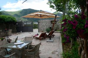 a patio with a table and chairs and an umbrella at Lazovic- Apartment by the Sea with Amazing View in Dobrota
