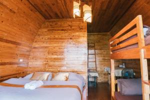 a bedroom with a bed in a wooden wall at Phumork Camp Phu Chi Fa in Ban Huai Han