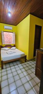 a bedroom with a bed in a yellow room at Hostel Beach in Porto Seguro