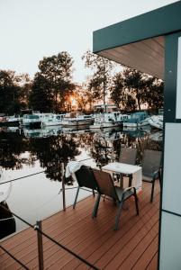 a table and chairs sitting on a deck next to a marina at Hausboot Urlaub in Ostfriesland auf der Waterhome 1 in Großefehn 