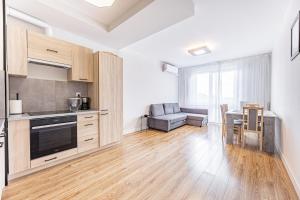une cuisine avec des placards en bois et un salon dans l'établissement Fajny apartament z parkingiem, obok metra., à Varsovie