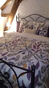 a bed with a floral blanket and pillows on it at La tour du logis, gîte 4 * à 15 min du Futuroscope in Chéneché