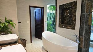 a bathroom with a large white tub and a sink at La VILLA MAELA GOLF ANAHITA in Beau Champ +34 photos