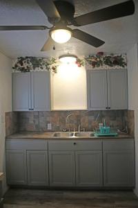 a kitchen with white cabinets and a ceiling fan at 1 bedroom with a fireplace close to base in Lawton