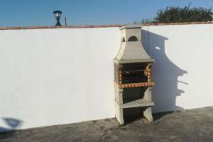 a brick oven on the side of a white wall at Casa Alejandra en el palmar in Cádiz