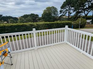 a white fence on a deck with a chair at Dog Friendly 8 Berth Static Caravan Newquay in Newquay