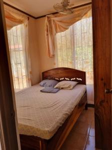 a bedroom with a canopy bed with two windows at Cabinas en Playas del Coco in Sardinal