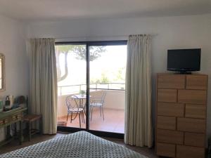 ein Schlafzimmer mit Fernseher und ein Balkon mit Tisch und Stühlen in der Unterkunft Habitación deluxe con baño privado en Atalaya Apartagolf, Estepona in Estepona