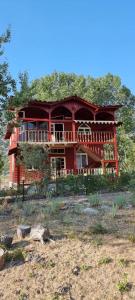 a red house on a hill with trees at Rrjoll beach House in Baks-Rrjoll