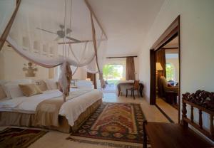 een slaapkamer met een groot bed met een baldakijn bij Swahili Beach in Diani Beach