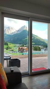 een kamer met een raam met uitzicht op de bergen bij appartamento PANORAMA in Pozza di Fassa
