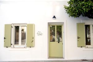 a white house with green shutters and a door at Eva's paradise Syros in Ermoupoli