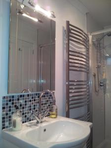 a bathroom with a sink and a mirror and a shower at Links Lodge in Lossiemouth