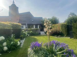 a garden with flowers and a church in the background at 't Hoppecruyt Logies in Proven