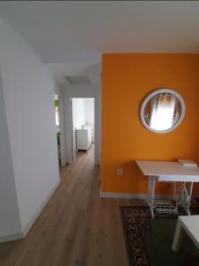 una stanza con una parete arancione con un tavolo e uno specchio di Alojamiento tresdiva a El Astillero Altre 8 foto