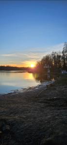 a sunset over a body of water with the sun setting at Haus am Nymphensee 4 in Brieselang