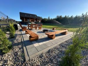 a group of wooden benches on a stone patio at Dom z Bala Serwy in Płaska