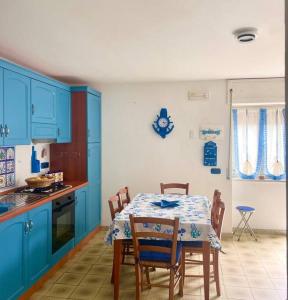una cucina con mobili blu e un tavolo con sedie di La casa sul blu Acciaroli Casa Vacanze ad Acciaroli