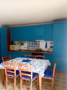 una cucina con armadi blu, tavolo e sedie di La casa sul blu Acciaroli Casa Vacanze ad Acciaroli