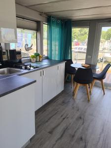 a kitchen with white cabinets and a table and chairs at MOONLIGHT HOUSEBOAT in Świnoujście