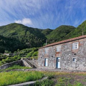 a stone building with mountains in the background at Casas Dos Vimes in Fajã dos Vimes
