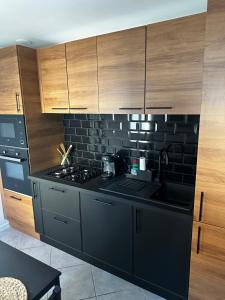 a kitchen with black counters and wooden cabinets at La Perle charmante maison avec parking privé in Mers-les-Bains +28 photos