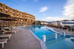 ein Swimmingpool in einem Ferienresort mit Liegestühlen und Sonnenschirmen in der Unterkunft Evia Hotel & Suites in Marmarion