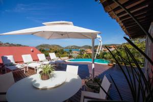 un patio con tavoli, ombrellone e piscina di Villa Vermelha Ocean View a Búzios