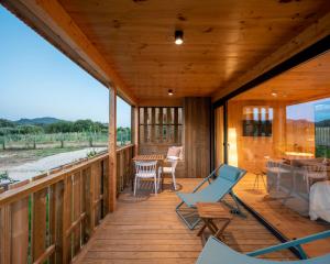 a large wooden porch with chairs and a table at Cabañas de Aldán in Aldán