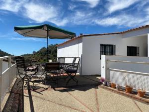 a patio with two chairs and an umbrella at Alojamiento El Monasterio in Almonaster la Real