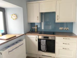 a kitchen with white cabinets and a black oven at Oldshorecroft in Sheigra