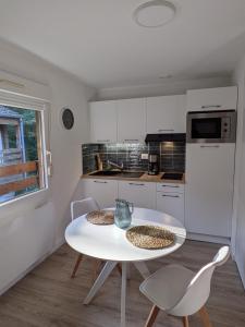 Una cocina blanca con una mesa y sillas blancas. en Studio centre thermal touristique - Casa Amnéville, en Amnéville
