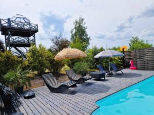 a deck with chairs and umbrellas next to a swimming pool at Namiot glampingowy Forest in Krzesimów