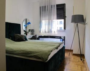Un dormitorio con una cama con una lámpara y una ventana. en Plava orhideja apartman, en Trebinje