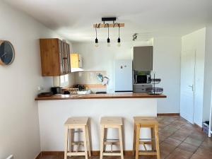 a kitchen with three bar stools and a counter at Maison Familiale Proche Plage, Marché & Commerces - 6 pers. Classée 3 étoiles in La Brée-les-Bains