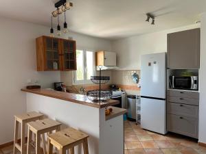 a kitchen with a white refrigerator and wooden stools at Maison Familiale Proche Plage, Marché & Commerces - 6 pers. Classée 3 étoiles in La Brée-les-Bains